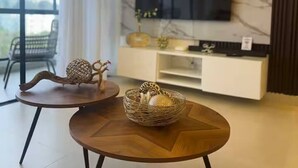 Ett modernt vardagsrum med en stor TV, en soffa och ett soffbord.