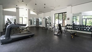 Un gimnasio con cintas de correr, máquinas de pesas y mancuernas.