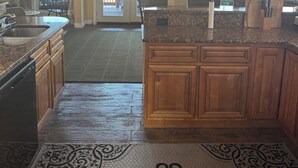A spacious kitchen with granite countertops, wooden cabinets, and a large island. There are two pendant lights, a built-in oven, and a view through the glass doors to the outside. - DERBY SPECIAL  includes parking spot 50 ft from the track . 6-bedroom lodge (Bloomfield)