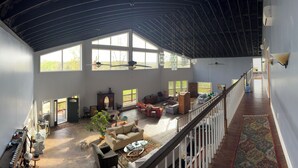 A spacious interior with a high ceiling, large windows, and a central seating area with multiple sofas and chairs. - DERBY SPECIAL  includes parking spot 50 ft from the track . 6-bedroom lodge (Bloomfield)