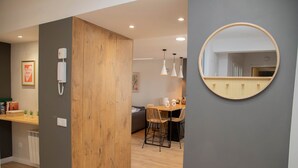 A modern kitchen with wooden cabinets, a dining area with a table and chairs, and a round mirror on the wall. - Cozy Loriga (Vigo)