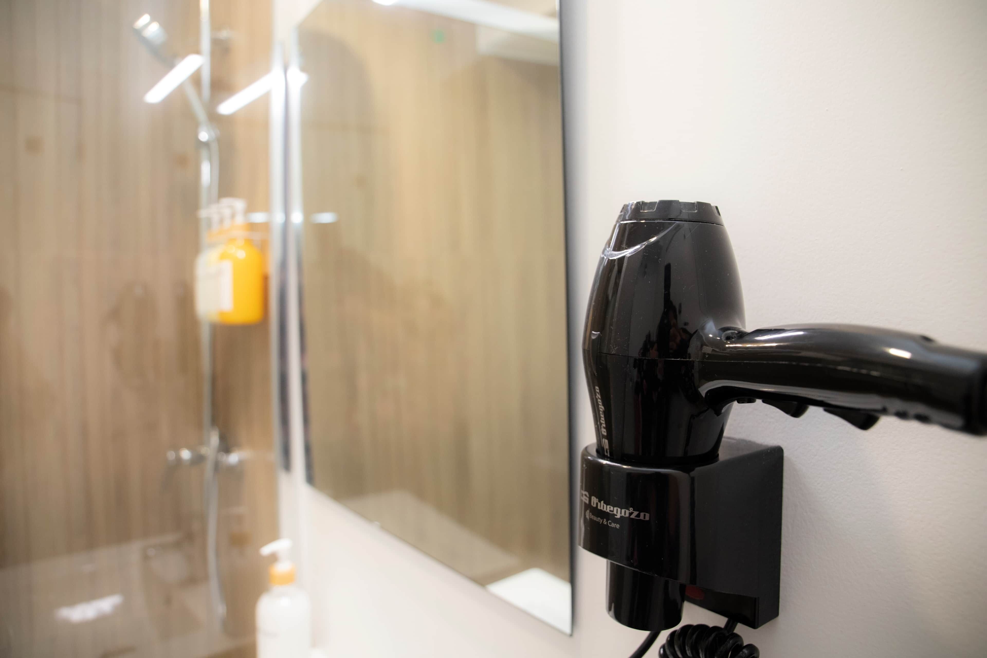 Un sèche-cheveux fixé au mur dans une salle de bain.