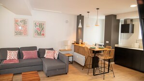 A modern living room with a grey sofa, wooden coffee table, and a kitchen area with a bar and dining chairs. - Cozy Loriga (Vigo)