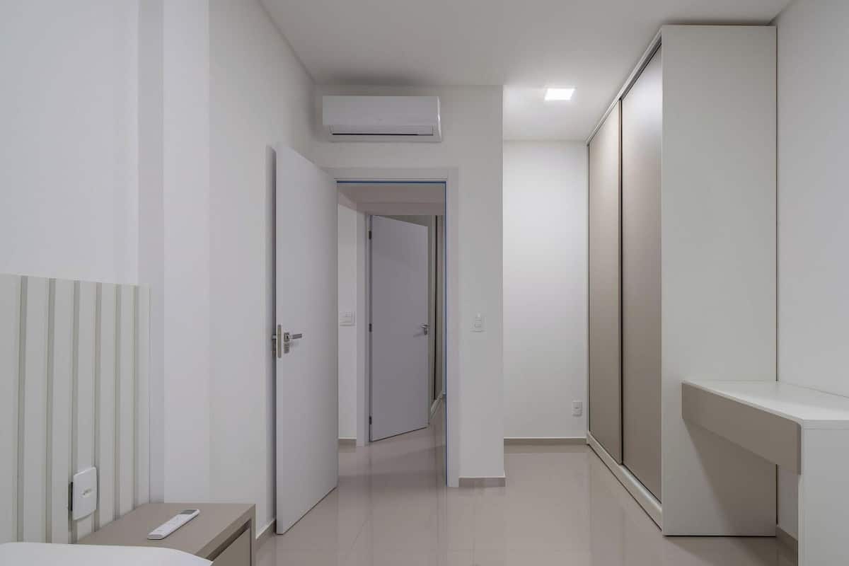 Ein modernes Hotelzimmer mit Bett, Nachttisch, Kleiderschrank und Klimaanlage.