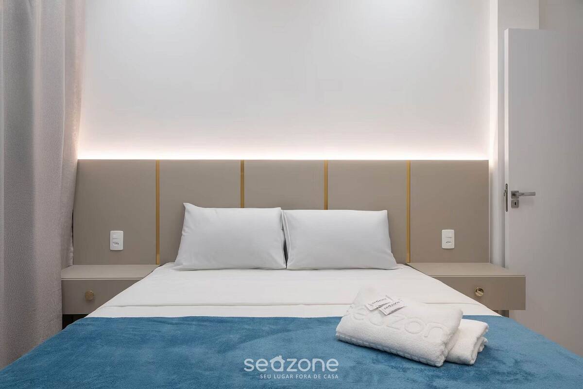 Ein Hotelzimmer mit Bett, Nachttisch und einer wandmontierten Lampe.