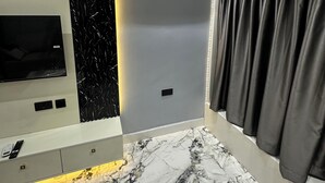 Ein modernes Badezimmer mit Marmorboden, integriertem Fernseher und einer wandmontierten Klimaanlage.