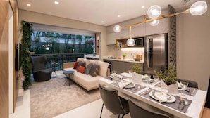 A modern kitchen with a built-in refrigerator, dining area with a table set for four, and a balcony with a sofa and chairs. - Red calllitr (Goiânia)
