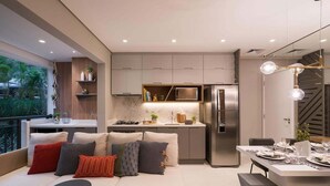 A modern kitchen with built-in appliances, a dining area with a white table set for four, and a cozy seating area with a sofa and cushions. - Red calllitr (Goiânia)