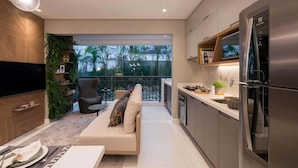 A modern kitchen with a built-in refrigerator, a dining area with a sofa, and a balcony with a view of palm trees. - Red calllitr (Goiânia)