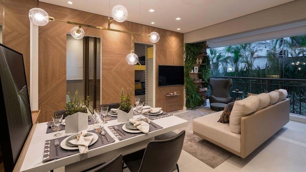 A modern dining area with a long table set for a meal, a sofa, and a TV in the background. - Red calllitr (Goiânia)
