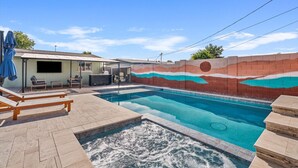 Zwembad met een jacuzzi, ligbedden en een overdekt terras.