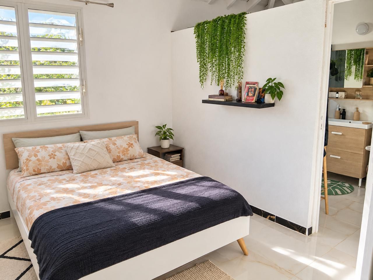 Un dormitorio con cama, mesita de noche, planta colgante y estante con libros y un marco de fotos.