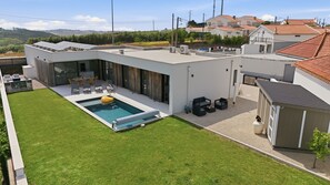 A modern house with a swimming pool, outdoor seating, and a view of the surrounding area.