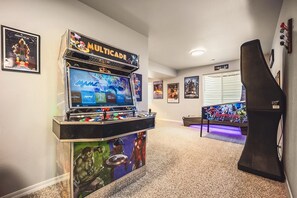 Una sala de juegos recreativos con una máquina Multicade, carteles y un área de descanso.