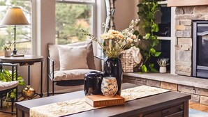 A cozy living room with a large window, a fireplace, a coffee table with decorative items, and a comfortable seating area. - Lakefront Spa Luxe • Theater & Game & View • USAFA 10 Min • Sleeps 10 (Monument)