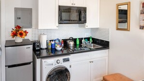 Uma cozinha compacta com máquina de lavar, micro-ondas e pia.