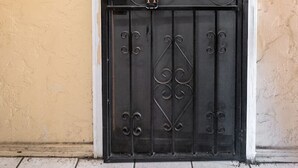 Um portão de metal preto com uma fechadura e o número 11 numa parede bege.