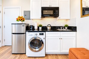 A compact kitchen with a stainless steel refrigerator, an LG washing machine, a microwave, and white cabinetry. - Chic & Stylish Studio Near Downtown LA * W/D * AC (Los Angeles)