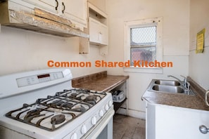 A kitchen with a gas stove, a sink, and cabinets.