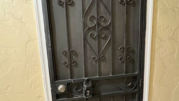 En svart metalldörr med dekorativa mönster och siffran 7.