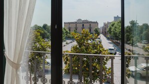 Een balkon met uitzicht op een straat, gebouwen en geparkeerde auto's.