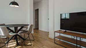 Een moderne woonkamer met een eettafel, stoelen, een televisie en een bank.