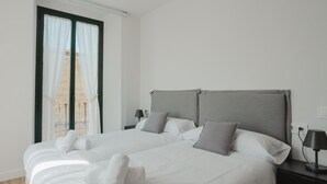 Une chambre d’hôtel moderne avec un grand lit, deux tables de chevet, une fenêtre avec des rideaux et une vue sur le paysage urbain.