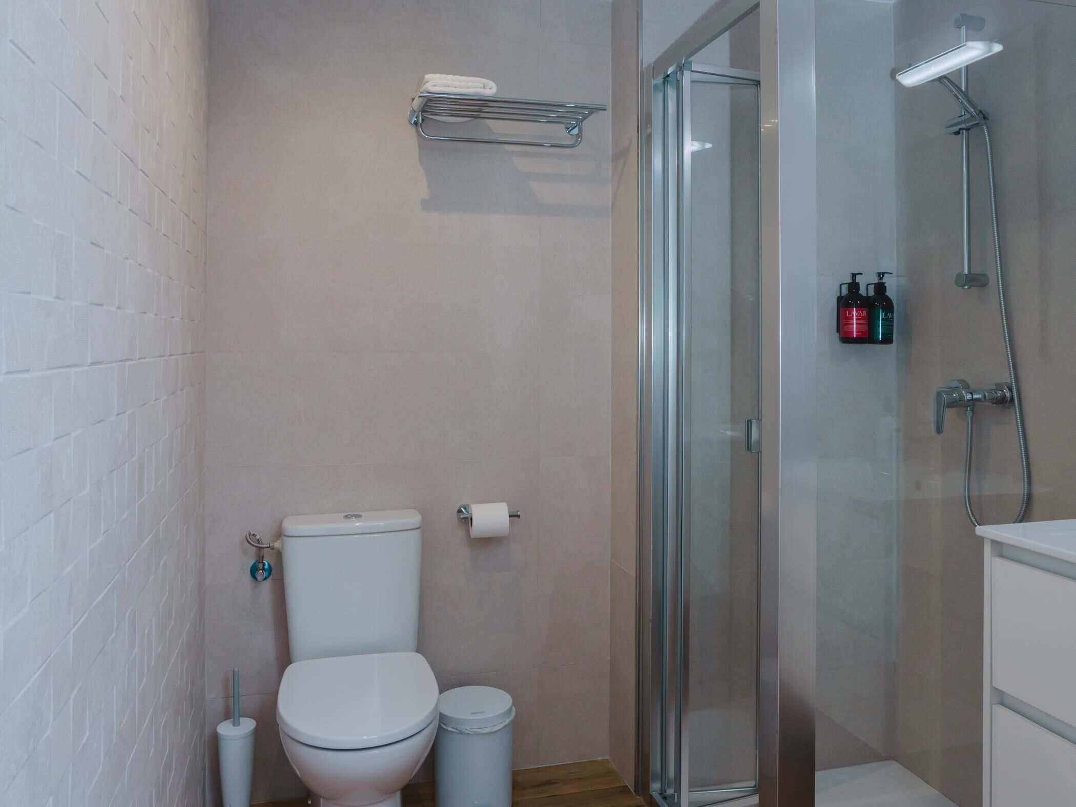 A modern bathroom with a toilet, a glass shower enclosure, and a sink.