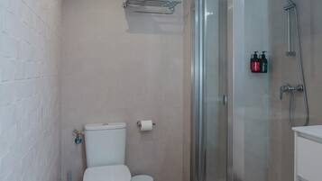A modern bathroom with a toilet, a glass shower enclosure, and a sink.