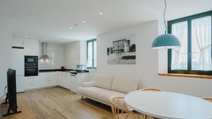 A modern kitchen with white cabinets, a built-in oven, and a dining area with a white table and wooden chairs.