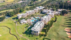 Un complexe hôtelier proposant des terrains de golf, comprenant plusieurs bâtiments, un espace piscine central et de vastes pelouses bien entretenues.