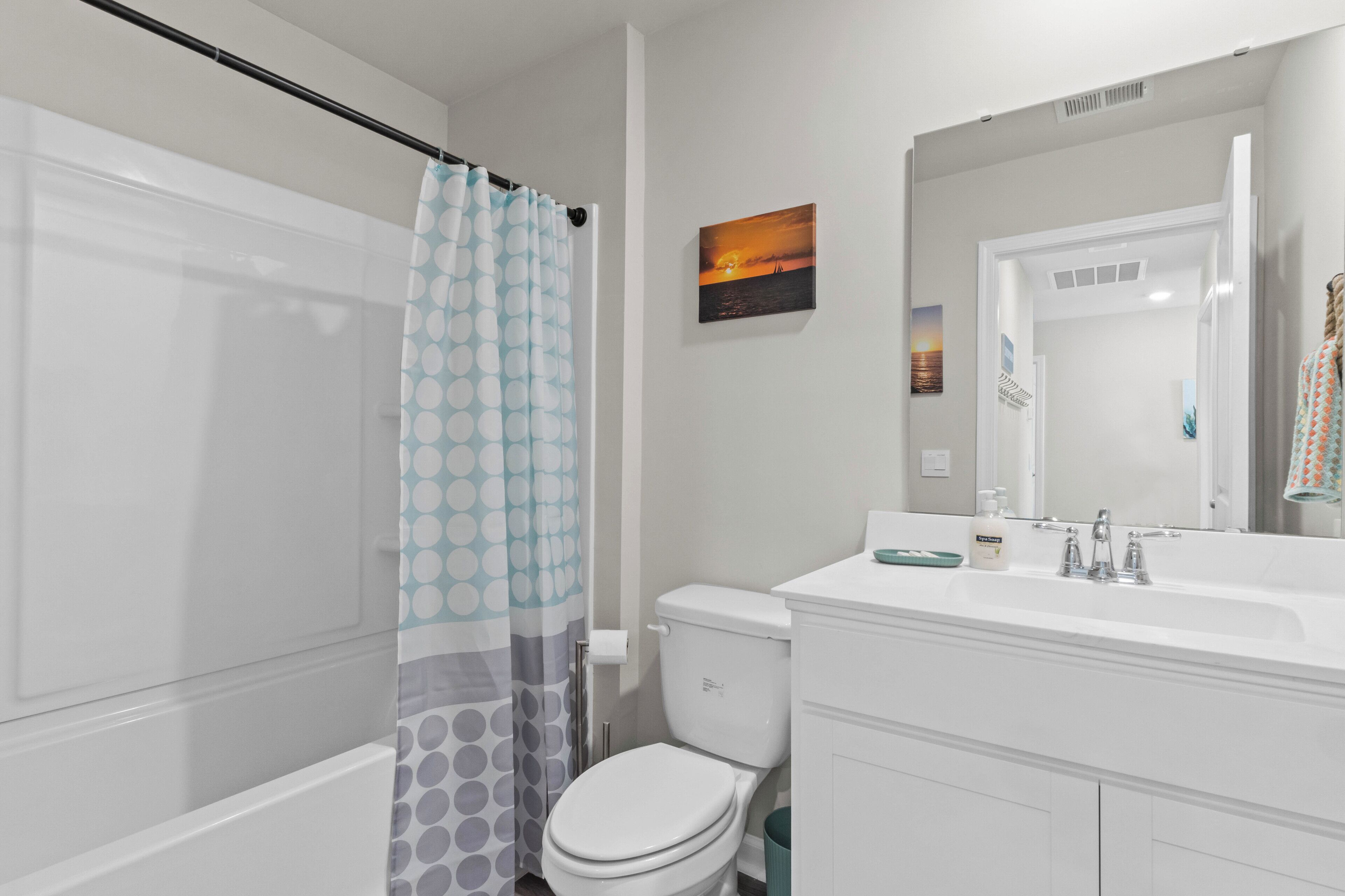 A bathroom with a shower, toilet, sink, and mirror.