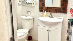Ein Badezimmer mit Toilette, Waschbecken, einem Spiegel mit Ziegelrahmen und einem Handtuchregal.