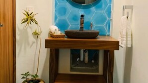 Une salle de bain avec un meuble-lavabo en bois, un miroir rond et un revêtement mural en carreaux bleus hexagonaux.