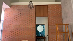Une pièce avec un mur en briques, une échelle en bois, une chaise en osier et un meuble en bois.