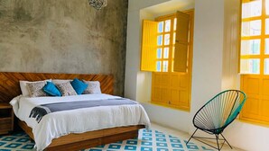 Une chambre à coucher avec un lit, une chaise et une fenêtre avec des volets jaunes.