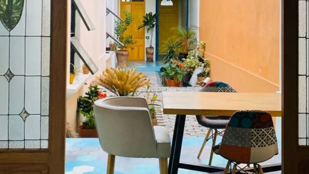 Vue intérieure d’un coin repas avec un sol carrelé en forme d’hexagone, une table en bois et deux chaises.