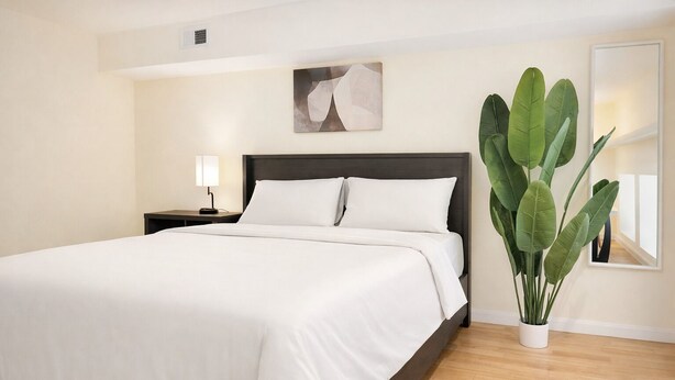 Une chambre à coucher moderne avec un grand lit, une table de chevet, une lampe de chevet et une plante en pot.