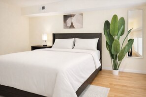 Una camera da letto moderna con un letto grande, un comodino, una lampada da tavolo e una pianta in vaso.