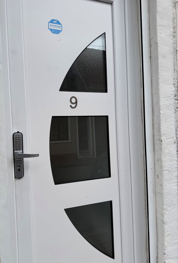 A white door with a number 9, a keypad lock, and a 24-hour service sticker. - Royal appart city 1 (Calais)