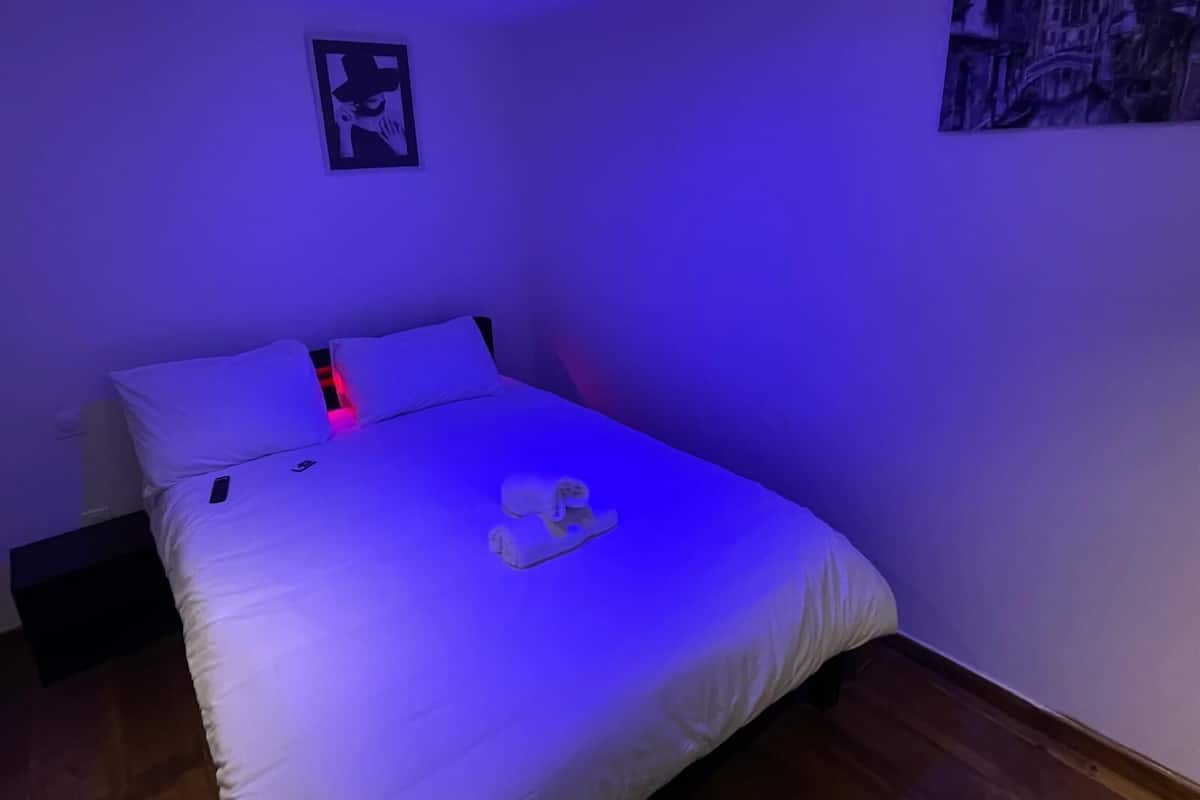 Ein Schlafzimmer mit einem Bett, einem Kissen, einer Decke und einem an der Wand hängenden Bild.