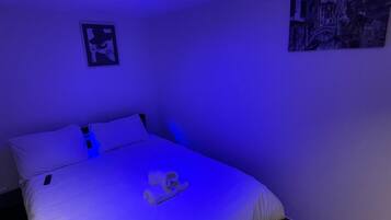 Een slaapkamer met een bed, kussens en een dekbed.