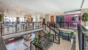 En rymlig interiör med flera våningsplan och modern design, med bland annat en trappa, sittgrupper och olika konstverk.