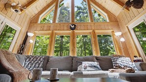 A wooden cabin with a high ceiling, large windows, a sofa with patterned cushions, and a mounted animal head. - Harbor Springs Lodge, Less then a mile to Nubs/Highlands
Ski,Golf, Hot Tub, (Harbor Springs)