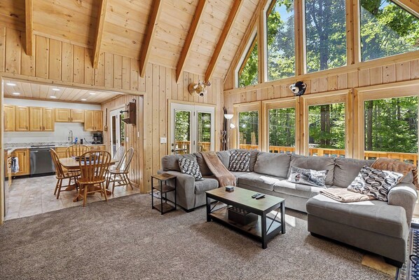 A spacious living area with a large window, a sofa, a coffee table, and a dining table with chairs.