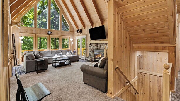 A wooden interior with a fireplace, a sofa, a television, and a staircase. - Harbor Springs Lodge, Less then a mile to Nubs/Highlands
Ski,Golf, Hot Tub, (Harbor Springs)