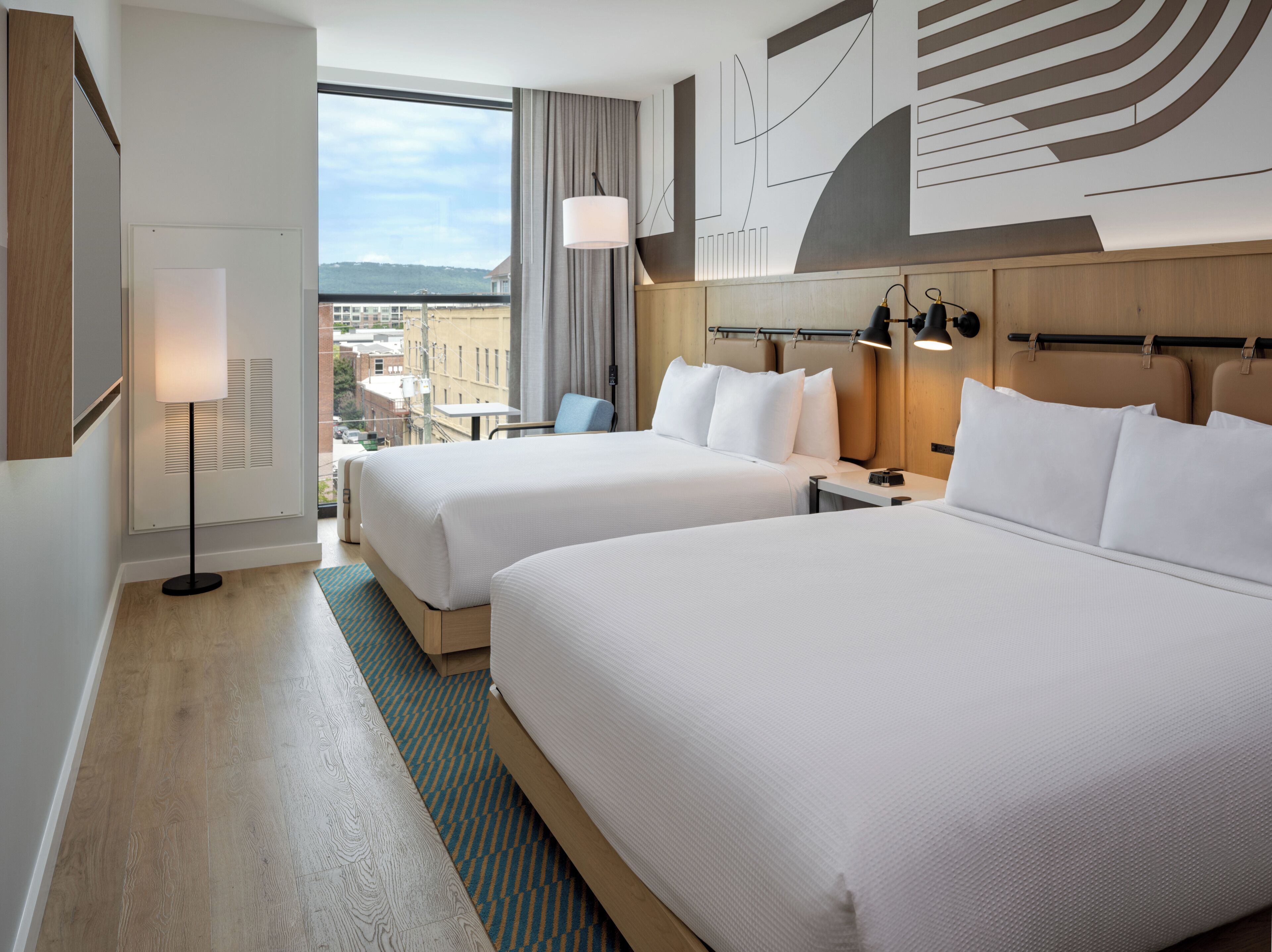 Habitación de hotel con dos camas, vistas a la ciudad y diseño moderno.