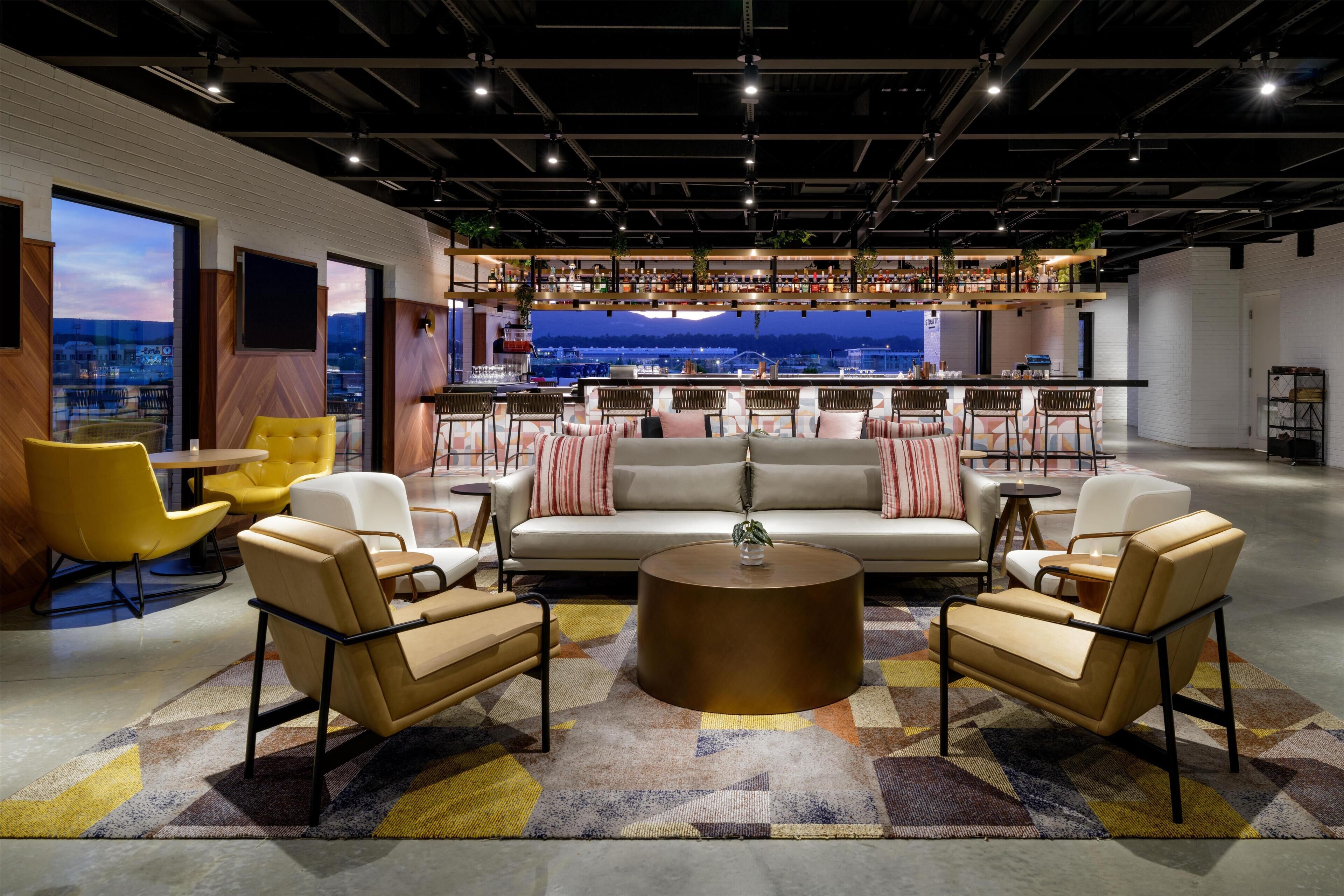 A modern lounge area with a sofa, chairs, and a bar.