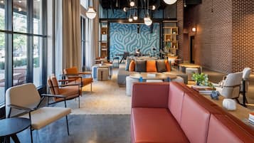 A modern lounge area with seating arrangements, a patterned wall, and a brick wall.