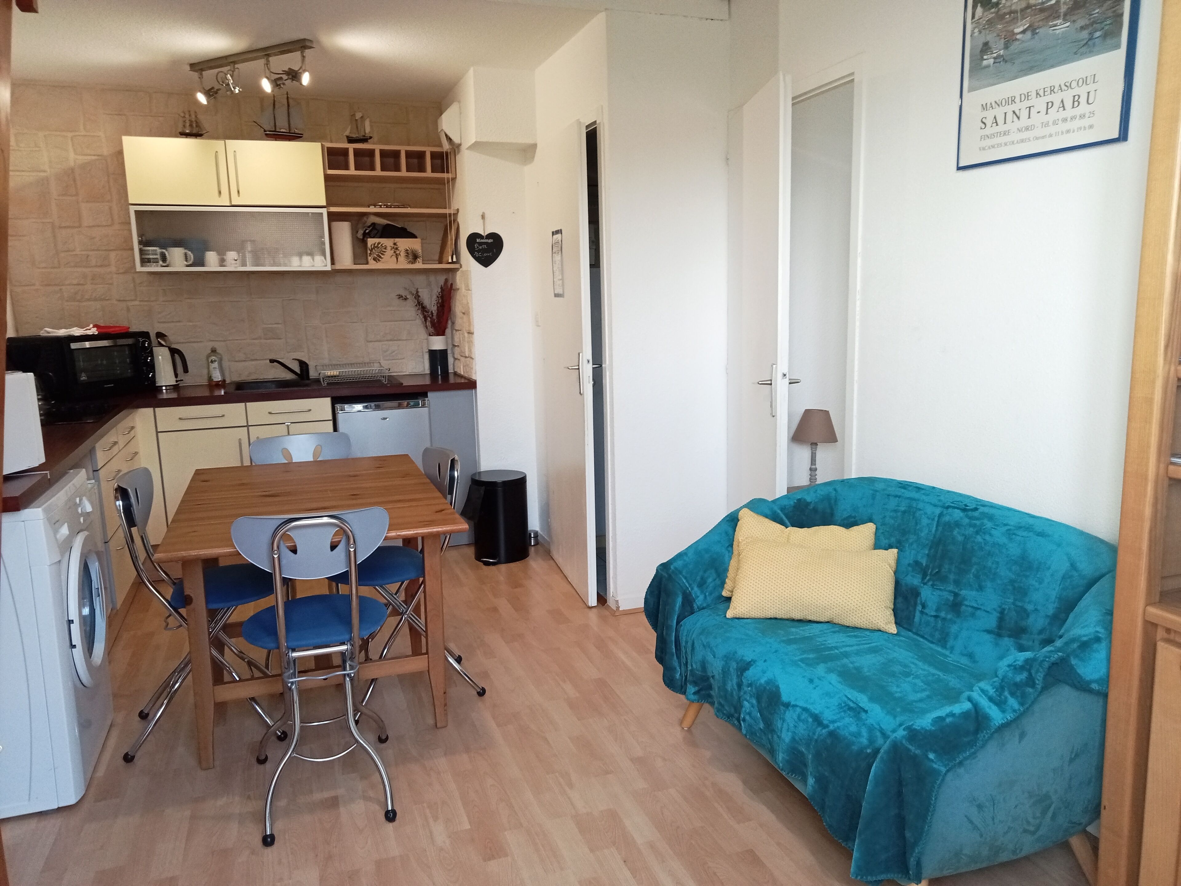 A compact living space with a kitchenette, dining area, and a blue sofa.